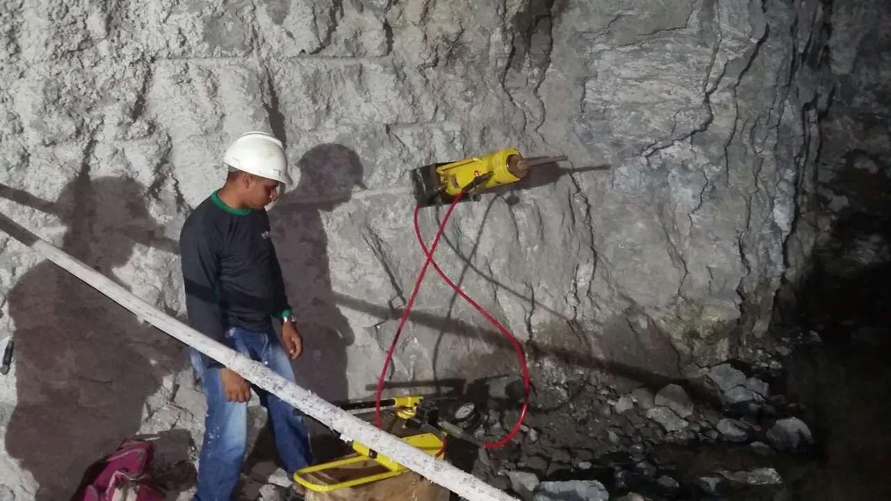 Profissional executando ensaio de arrancamento com macaco hidráulico e célula de carga em talude rochoso