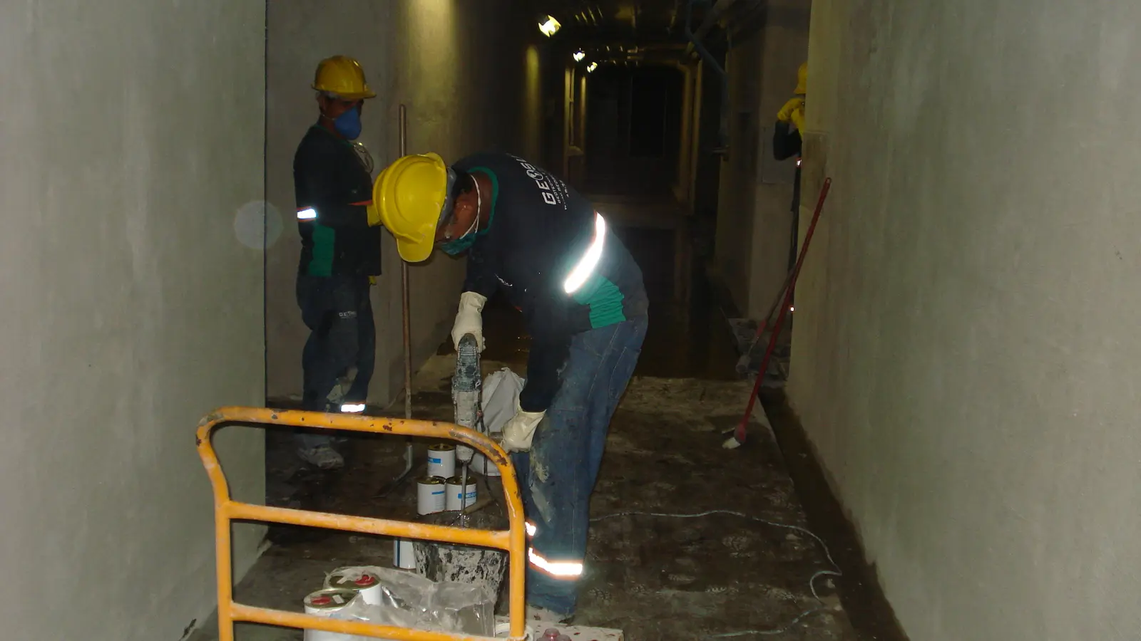 Dois profissionais trabalhando na base de um túnel estreito com iluminação artificial