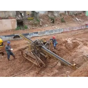 Perfuratriz e equipe executando grampos em talude de solo vermelho