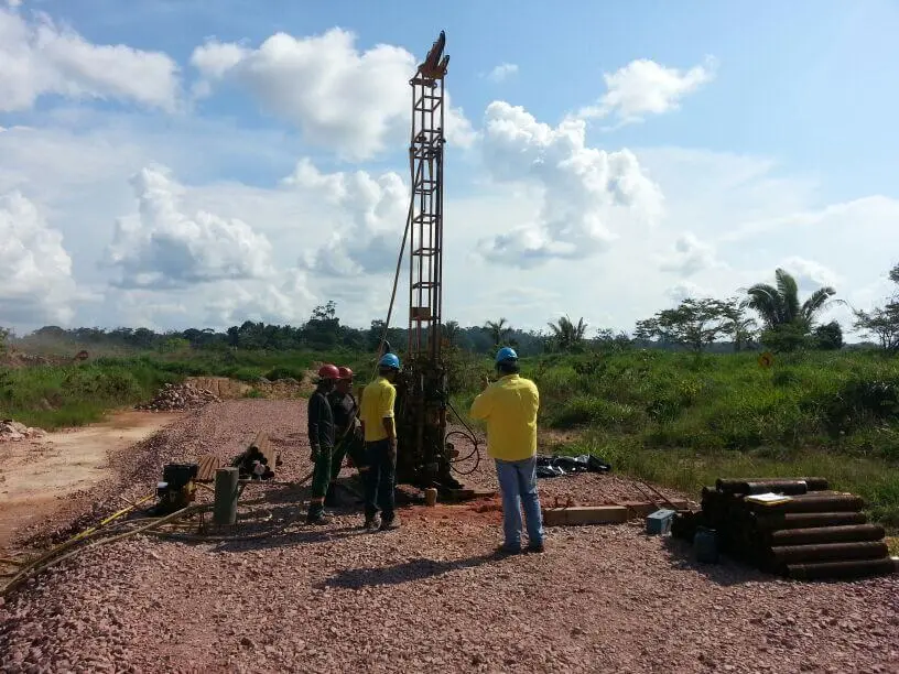 Equipe operando torre de sondagem à percussão em terreno aberto
