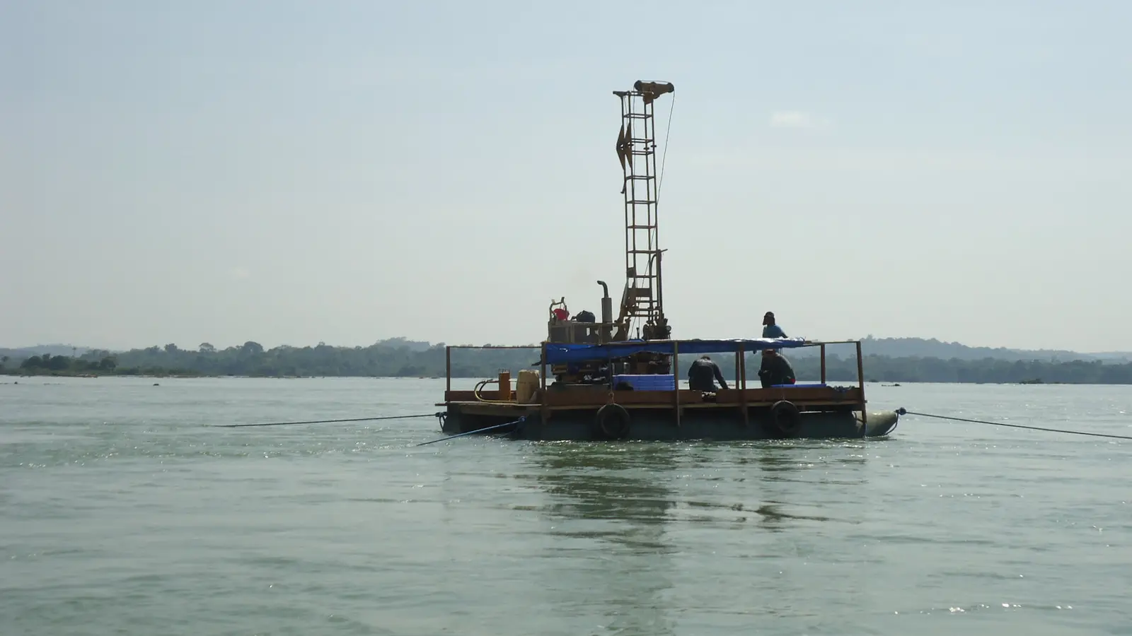 Plataforma flutuante com torre de sondagem no meio de um rio largo