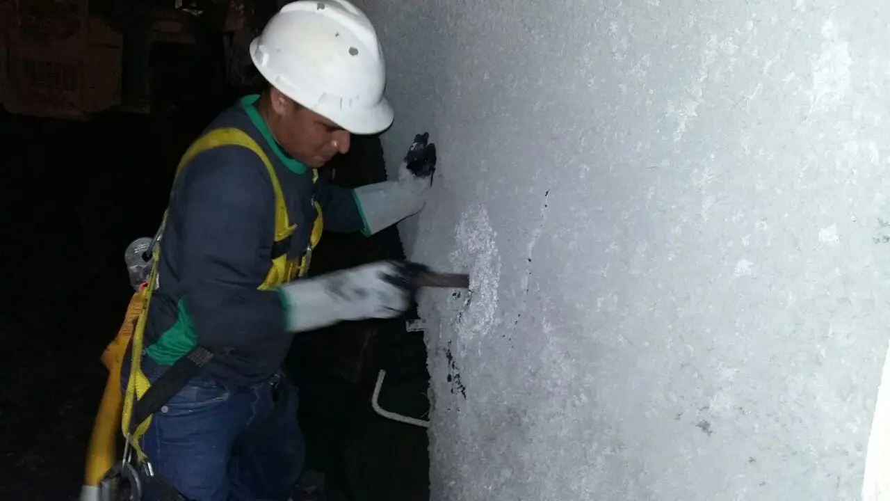 Profissional aplicando material de tratamento em parede de concreto no interior de um túnel